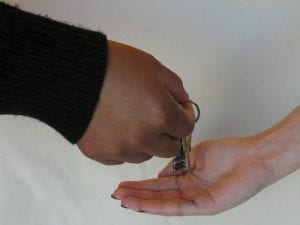Photo of keys been passed from one person's hand to another. 
